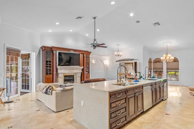 kitchen featuring a kitchen island with sink, sink, decorative light fixtures, and stainless steel dishwasher