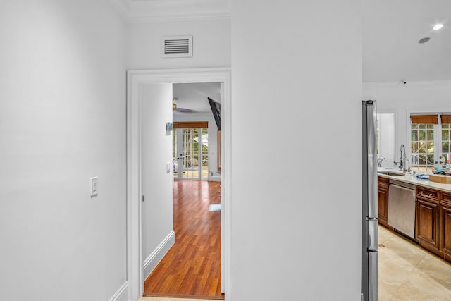 hallway with ornamental molding, sink, and light tile patterned floors