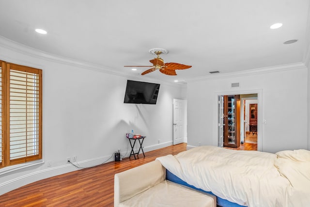 bedroom featuring crown molding, ceiling fan, wood-type flooring, and multiple windows