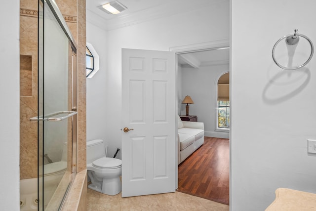 bathroom with crown molding, a shower with shower door, tile patterned floors, and toilet