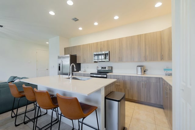 kitchen with sink, stainless steel appliances, a breakfast bar, and a center island with sink