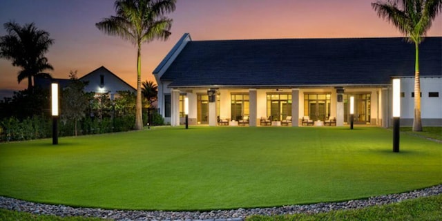 back of house at dusk featuring a yard