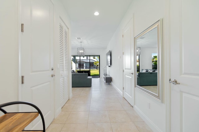 hall featuring light tile patterned floors and a notable chandelier