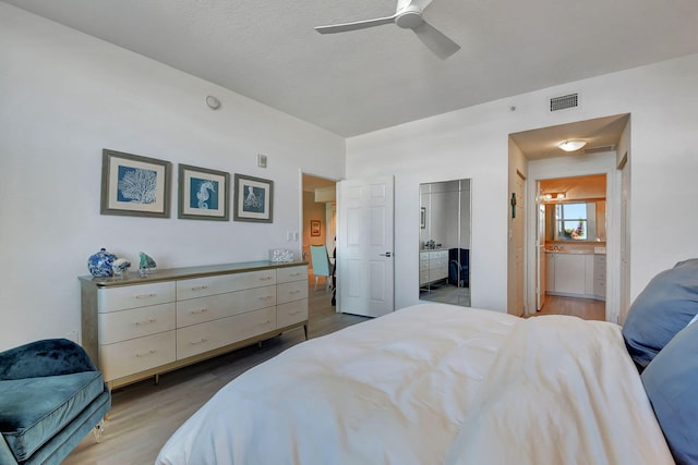 bedroom featuring ensuite bath, light hardwood / wood-style flooring, ceiling fan, a textured ceiling, and a closet