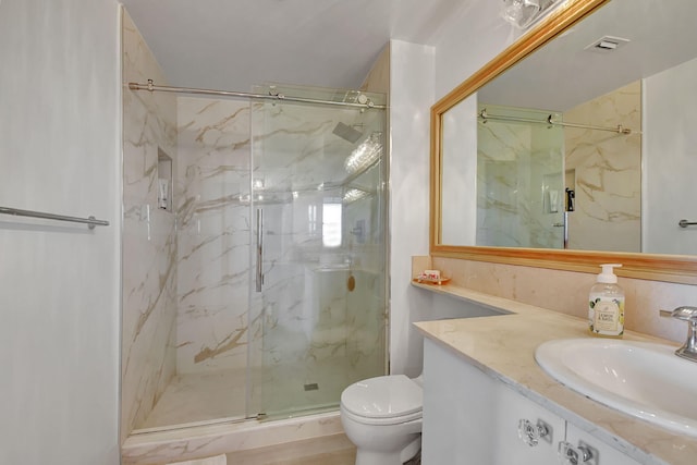 bathroom featuring vanity, a shower with door, and toilet