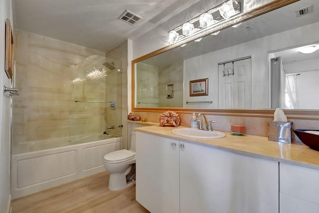 full bathroom with vanity, hardwood / wood-style floors, tiled shower / bath combo, and toilet