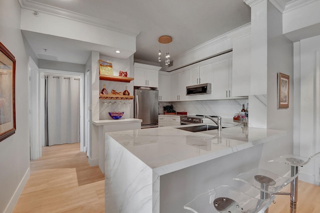 kitchen with appliances with stainless steel finishes, tasteful backsplash, white cabinetry, light hardwood / wood-style floors, and kitchen peninsula