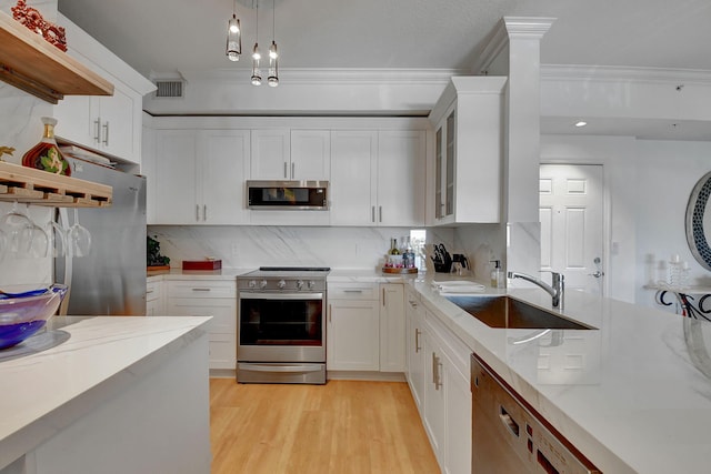 kitchen with pendant lighting, sink, appliances with stainless steel finishes, white cabinetry, and backsplash