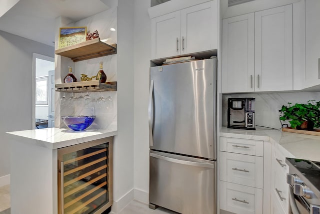 kitchen with white cabinets, beverage cooler, decorative backsplash, light stone counters, and stainless steel appliances