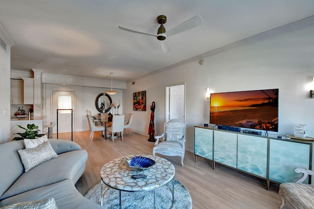 living room with crown molding, light hardwood / wood-style flooring, and ceiling fan