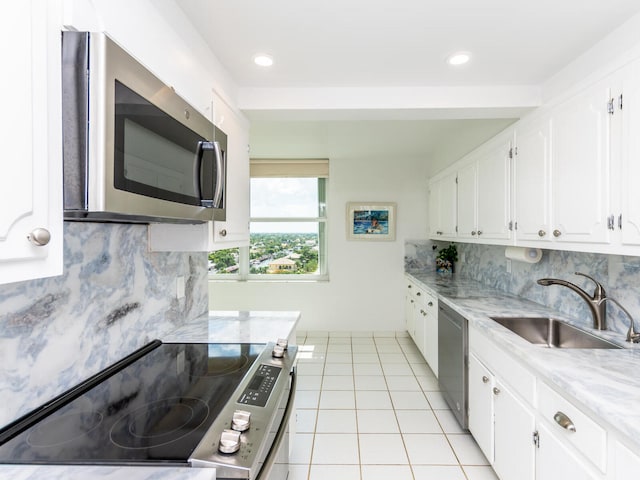 kitchen featuring sink, white cabinetry, light tile patterned floors, appliances with stainless steel finishes, and decorative backsplash