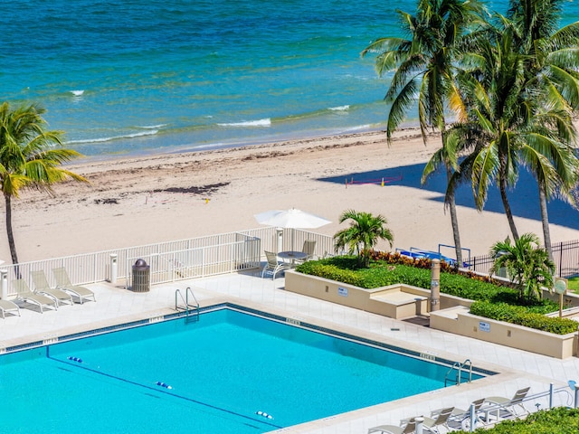 view of swimming pool featuring a patio area, a beach view, and a water view