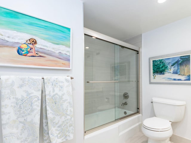 bathroom featuring bath / shower combo with glass door and toilet