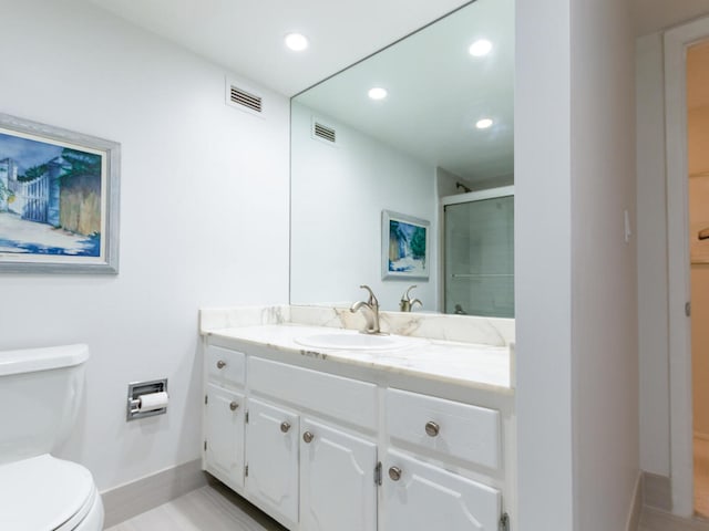 bathroom featuring vanity, a shower with shower door, and toilet