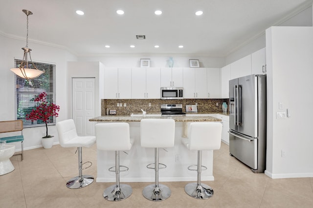 kitchen with light stone counters, crown molding, pendant lighting, stainless steel appliances, and white cabinets