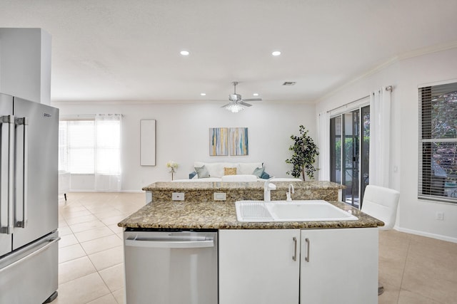 kitchen with stainless steel appliances, sink, a center island with sink, and light tile patterned floors