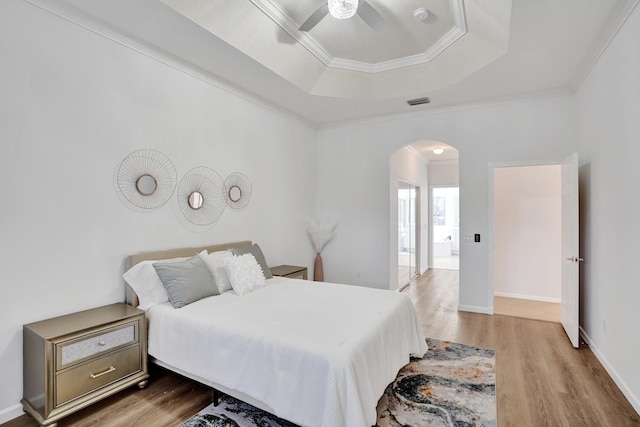 bedroom featuring crown molding, a tray ceiling, ceiling fan, and hardwood / wood-style flooring