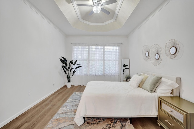 bedroom with a raised ceiling, wood-type flooring, ceiling fan, and crown molding