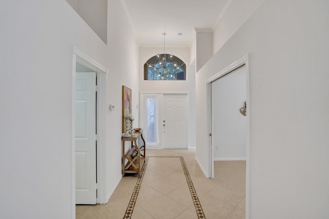 entryway with ornamental molding, a high ceiling, and a notable chandelier