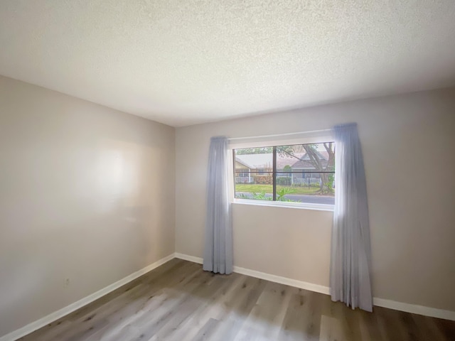 empty room with a textured ceiling and light hardwood / wood-style flooring