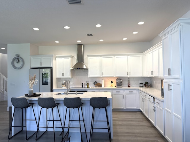 kitchen with stainless steel refrigerator, white cabinetry, sink, dark wood-type flooring, and wall chimney range hood