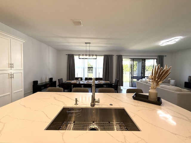 kitchen featuring hanging light fixtures, a wealth of natural light, sink, and white cabinets