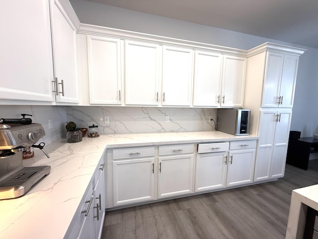 kitchen with white cabinetry, light stone countertops, and light hardwood / wood-style flooring