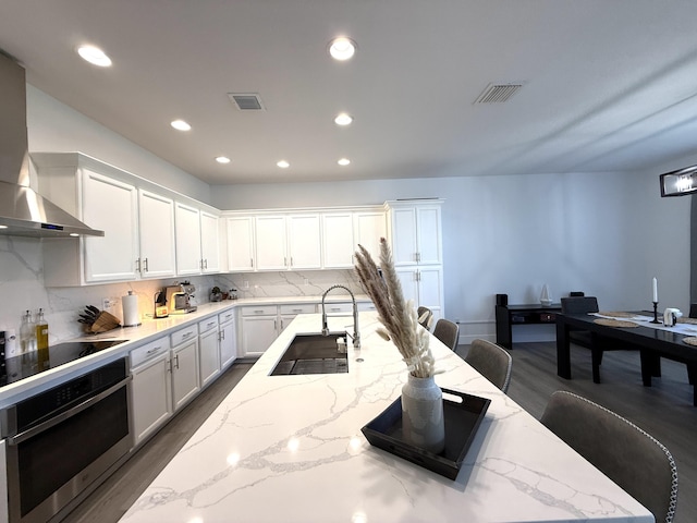 kitchen with stainless steel oven, a kitchen bar, light stone countertops, and white cabinets