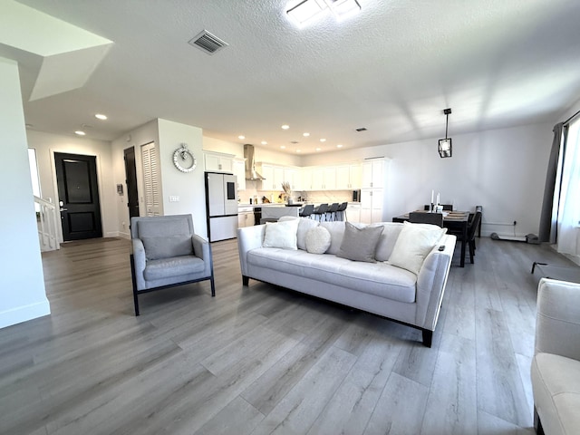 living room with a textured ceiling and light wood-type flooring