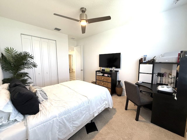 bedroom featuring white fridge, light colored carpet, ceiling fan, and a closet