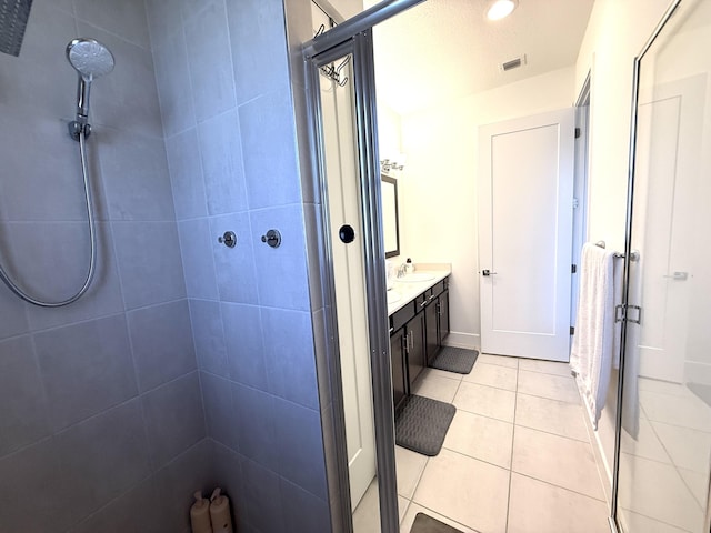 bathroom with vanity, tile patterned flooring, and a tile shower