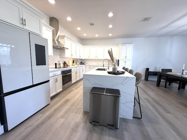 kitchen featuring white cabinets, fridge, oven, and wall chimney exhaust hood