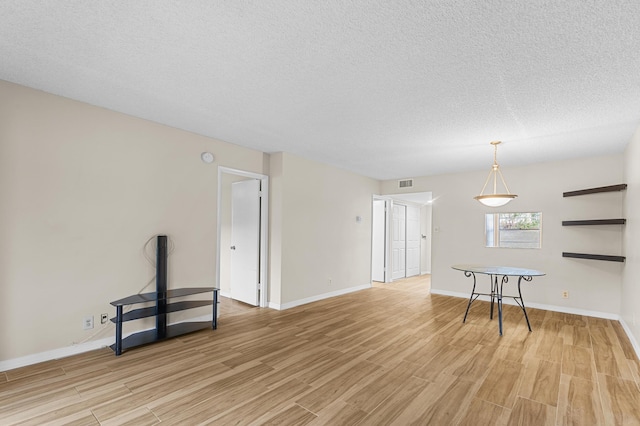 unfurnished room featuring a textured ceiling and light wood-type flooring