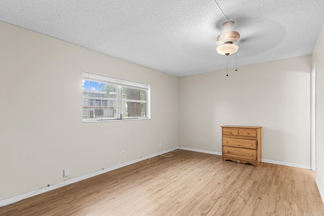 unfurnished room with ceiling fan, a textured ceiling, and light wood-type flooring