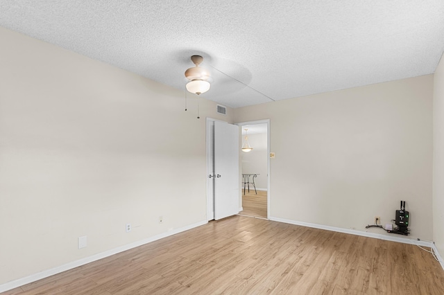 empty room with ceiling fan, a textured ceiling, and light wood-type flooring