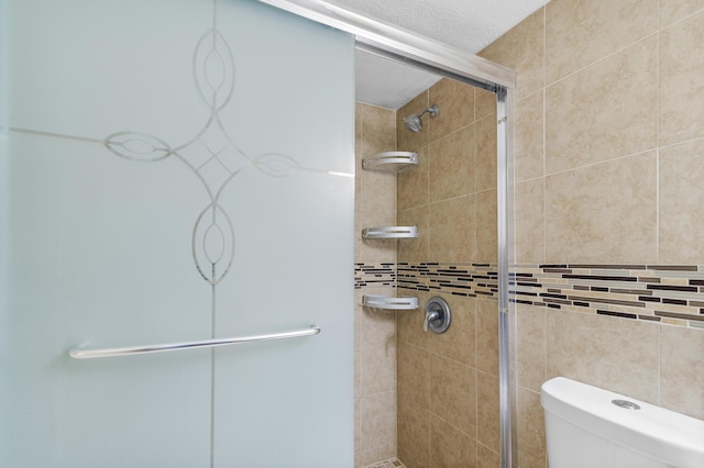 bathroom featuring toilet, a shower with shower door, and a textured ceiling