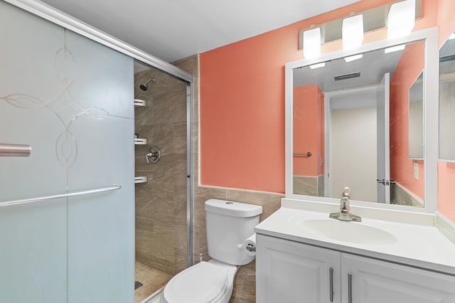 bathroom with vanity, toilet, an enclosed shower, and tile walls