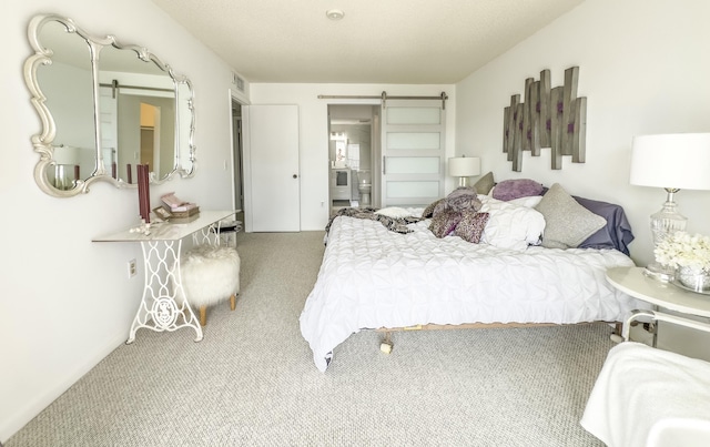 carpeted bedroom featuring a barn door and connected bathroom