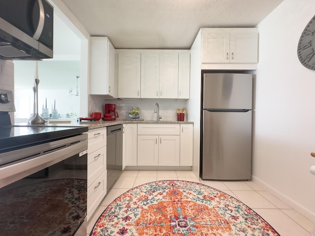 kitchen with white cabinetry, appliances with stainless steel finishes, sink, and light tile patterned flooring