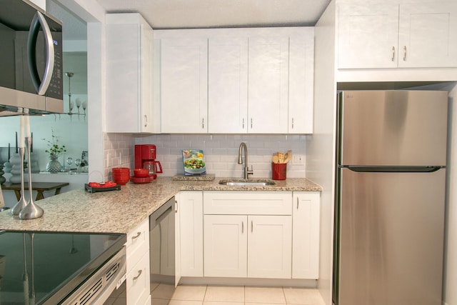 kitchen featuring stainless steel appliances, light stone countertops, sink, and white cabinets