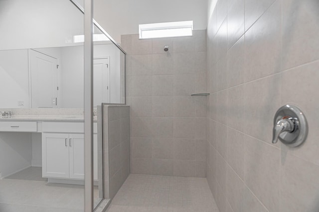 bathroom with tile patterned flooring, vanity, and a tile shower