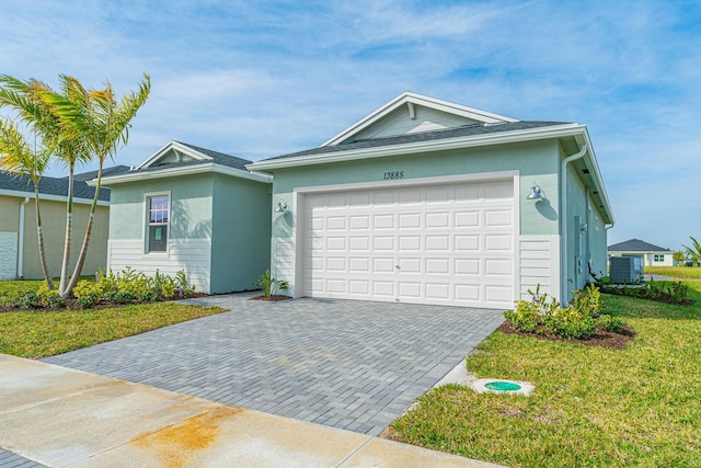 ranch-style home with a front yard, central AC unit, driveway, an attached garage, and stucco siding