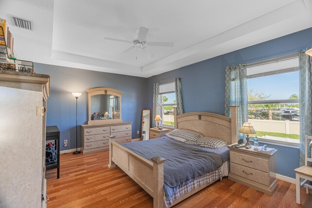 bedroom featuring hardwood / wood-style floors, ceiling fan, and a tray ceiling