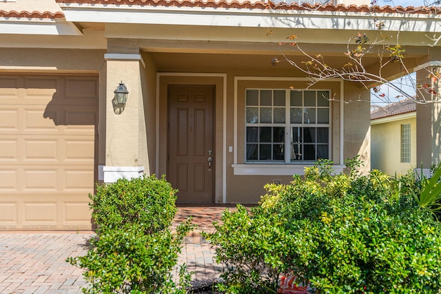 view of exterior entry featuring stucco siding and a tiled roof