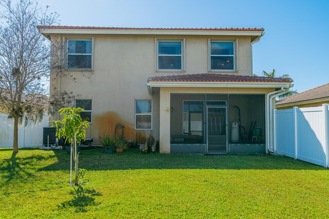 rear view of property featuring cooling unit, a lawn, and a sunroom