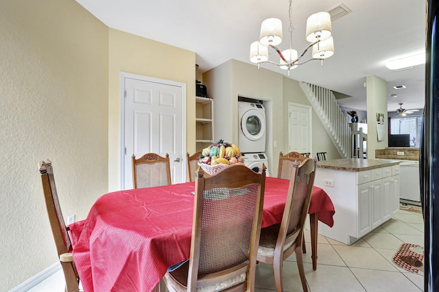 dining room featuring light tile patterned flooring, stacked washer and clothes dryer, and a notable chandelier