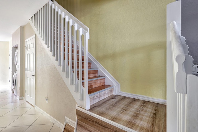 stairway featuring stacked washer and dryer and tile patterned flooring