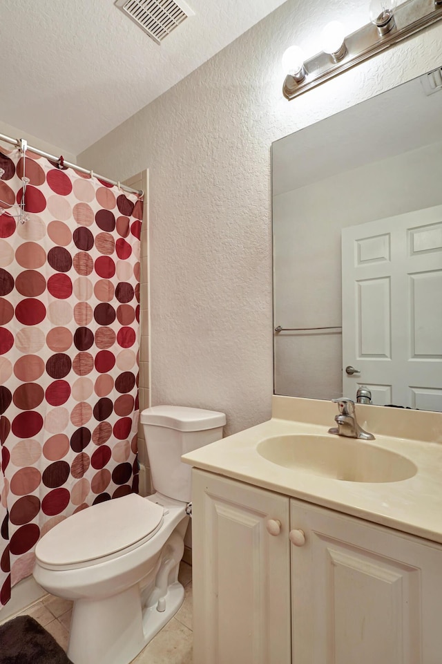 bathroom with tile patterned flooring, vanity, a textured ceiling, and toilet