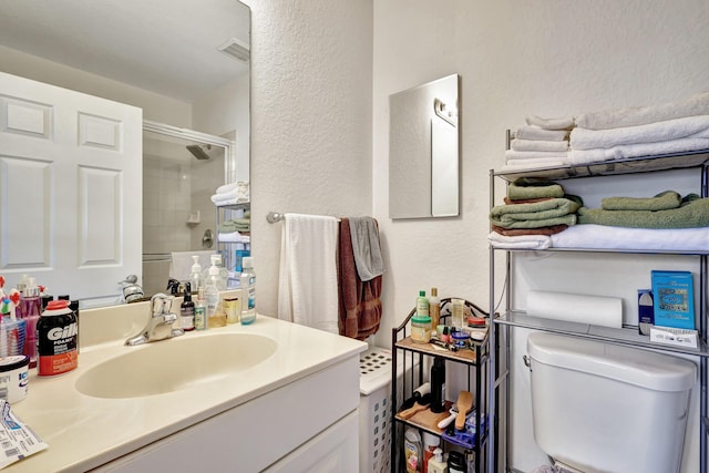 bathroom with toilet, vanity, and a shower with shower door