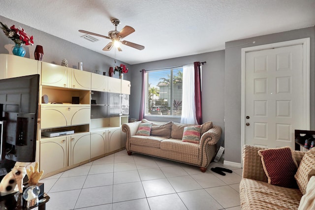 living room with ceiling fan, a textured ceiling, and light tile patterned floors